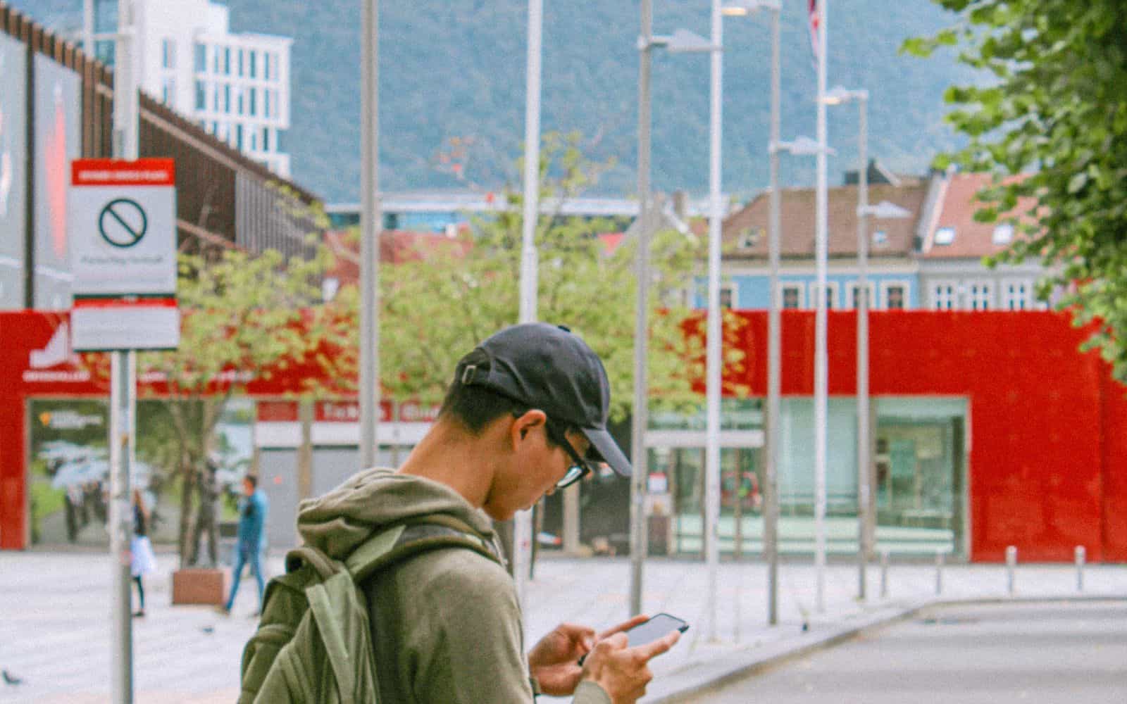 Mann sjekker mobilen utendørs i Bergen