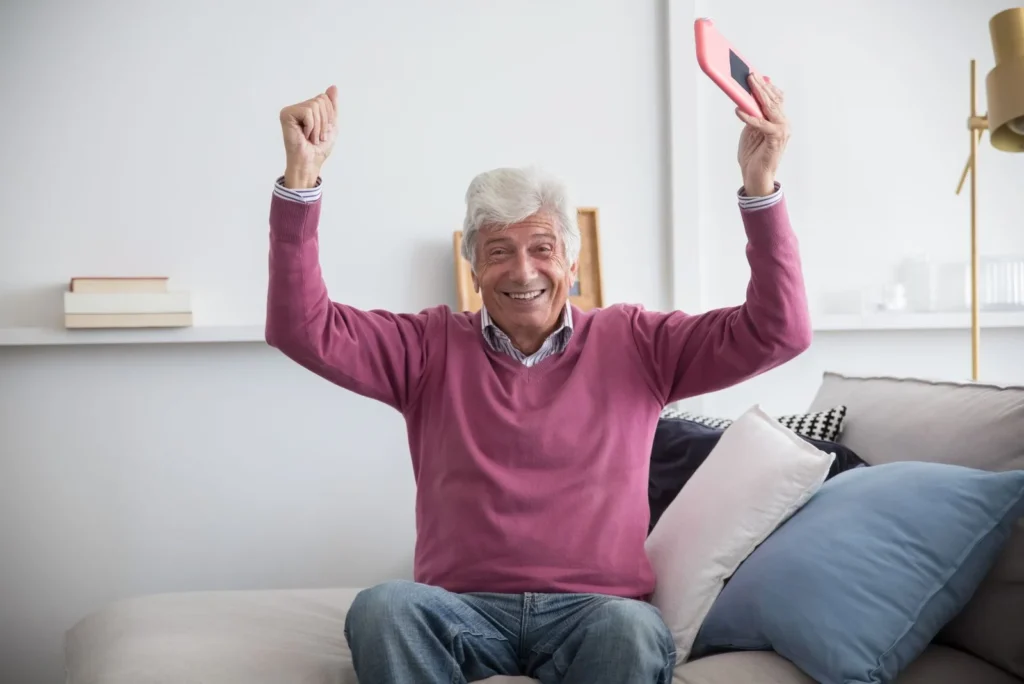 Fornøyd senior med mobil i sofaen