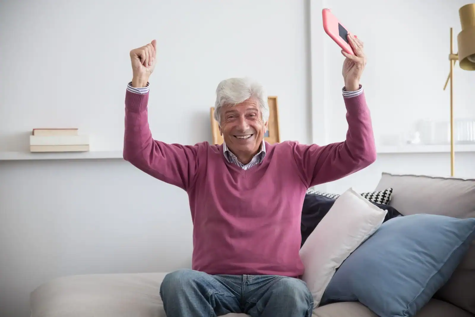 Fornøyd senior med mobil i sofaen