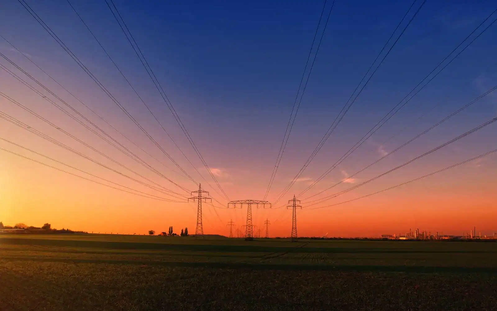 Kraftlinjer og master over et jorde i solnedgang