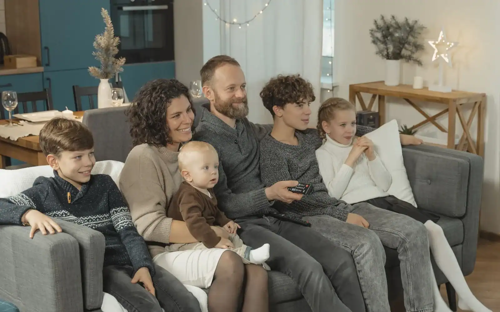 Familie på fem sitter tett i sofaen og ser på TV