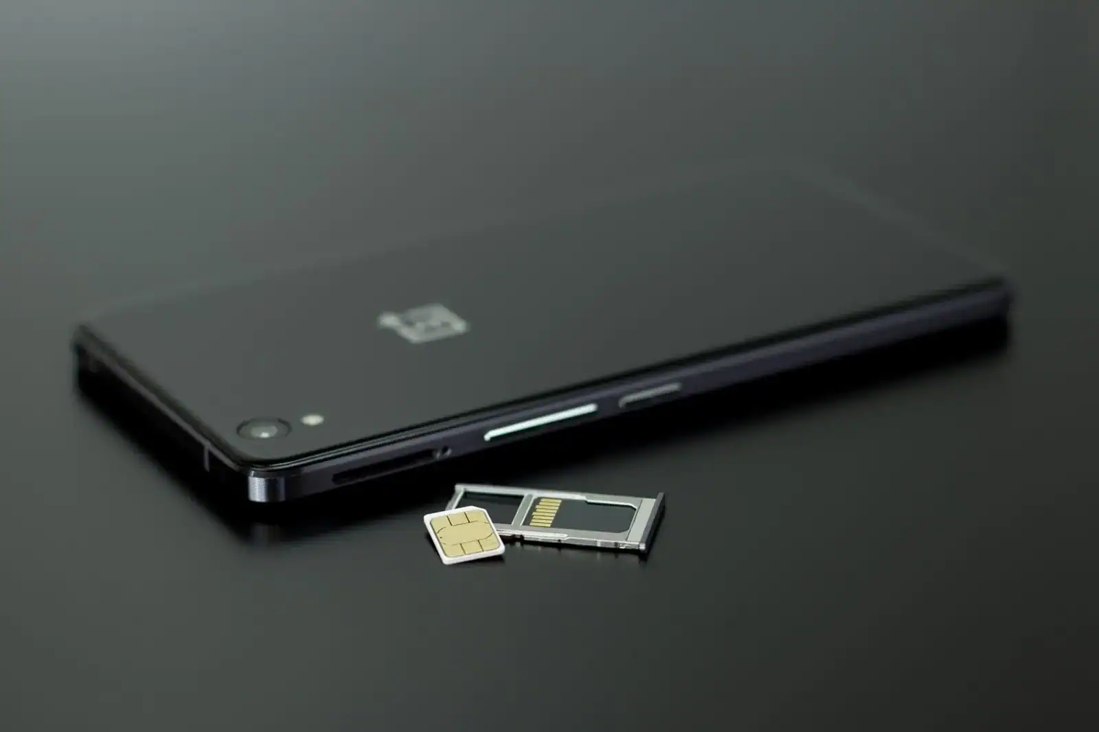 SIM-kort og mobiltelefon på mørk bakgrunn