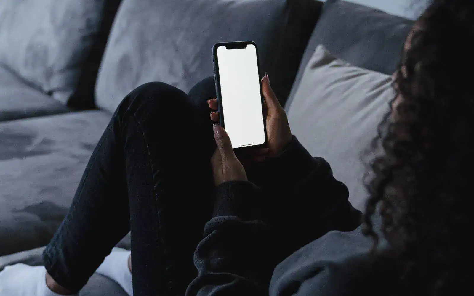 Person sjekker mobilen hjemme i sofaen