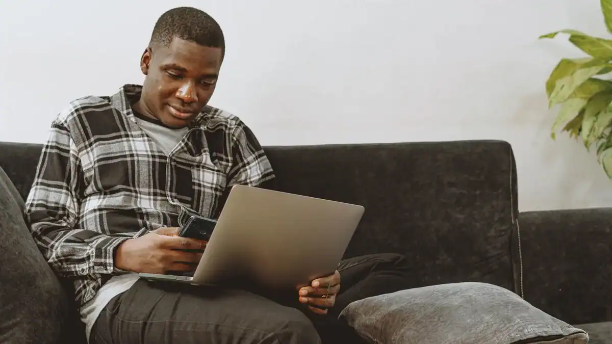 Mann i sofaen med laptop og mobil