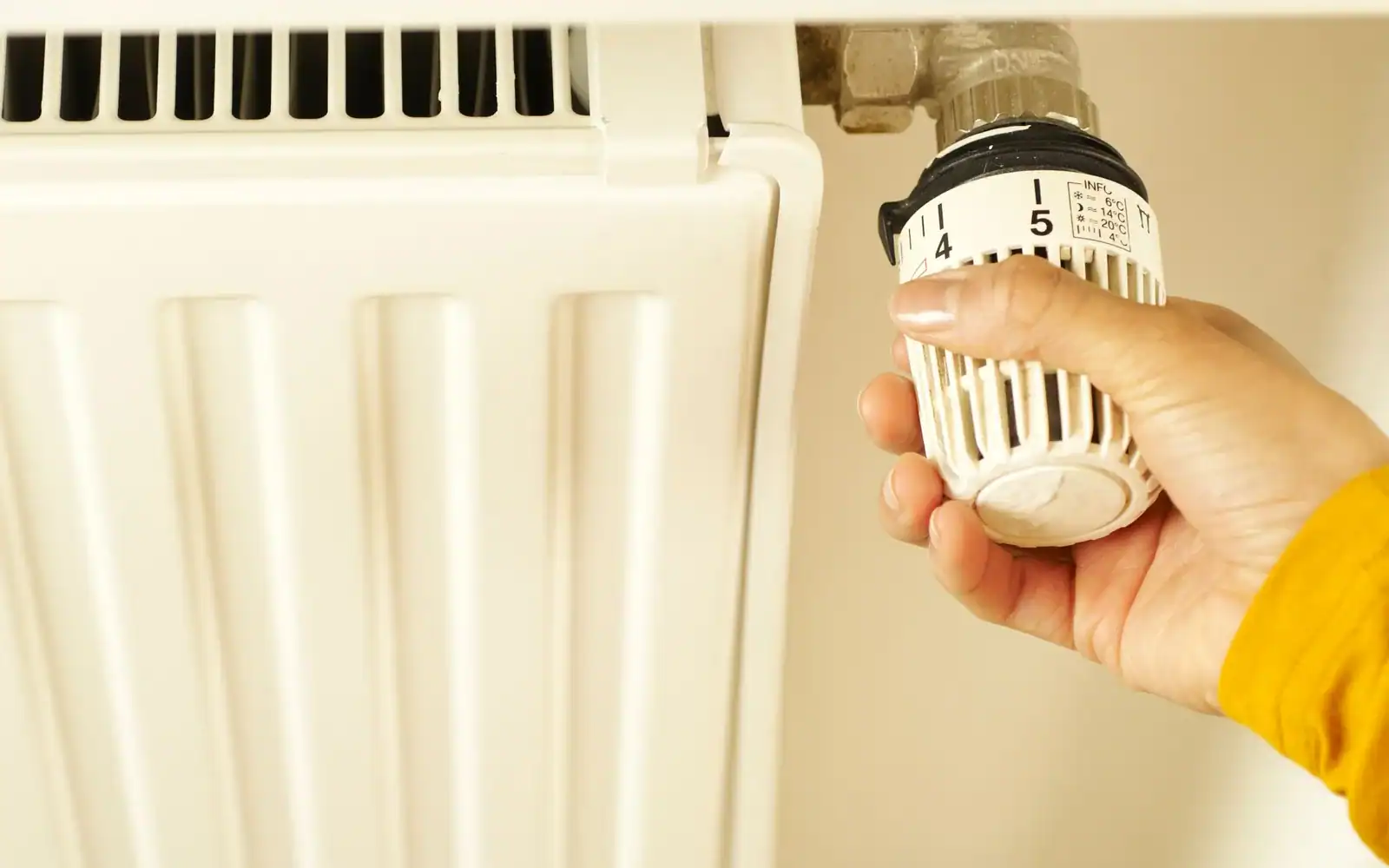 Hånd som skrur på termostaten på en radiator