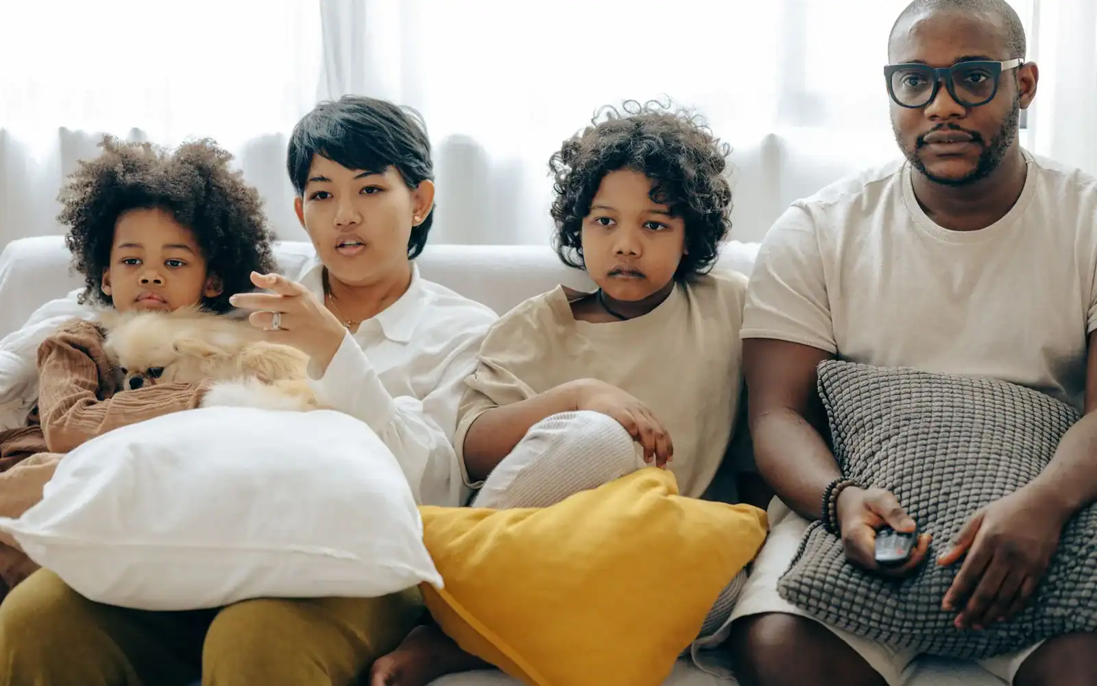 Familie med popcorn i sofaen ser konsentrert på TV